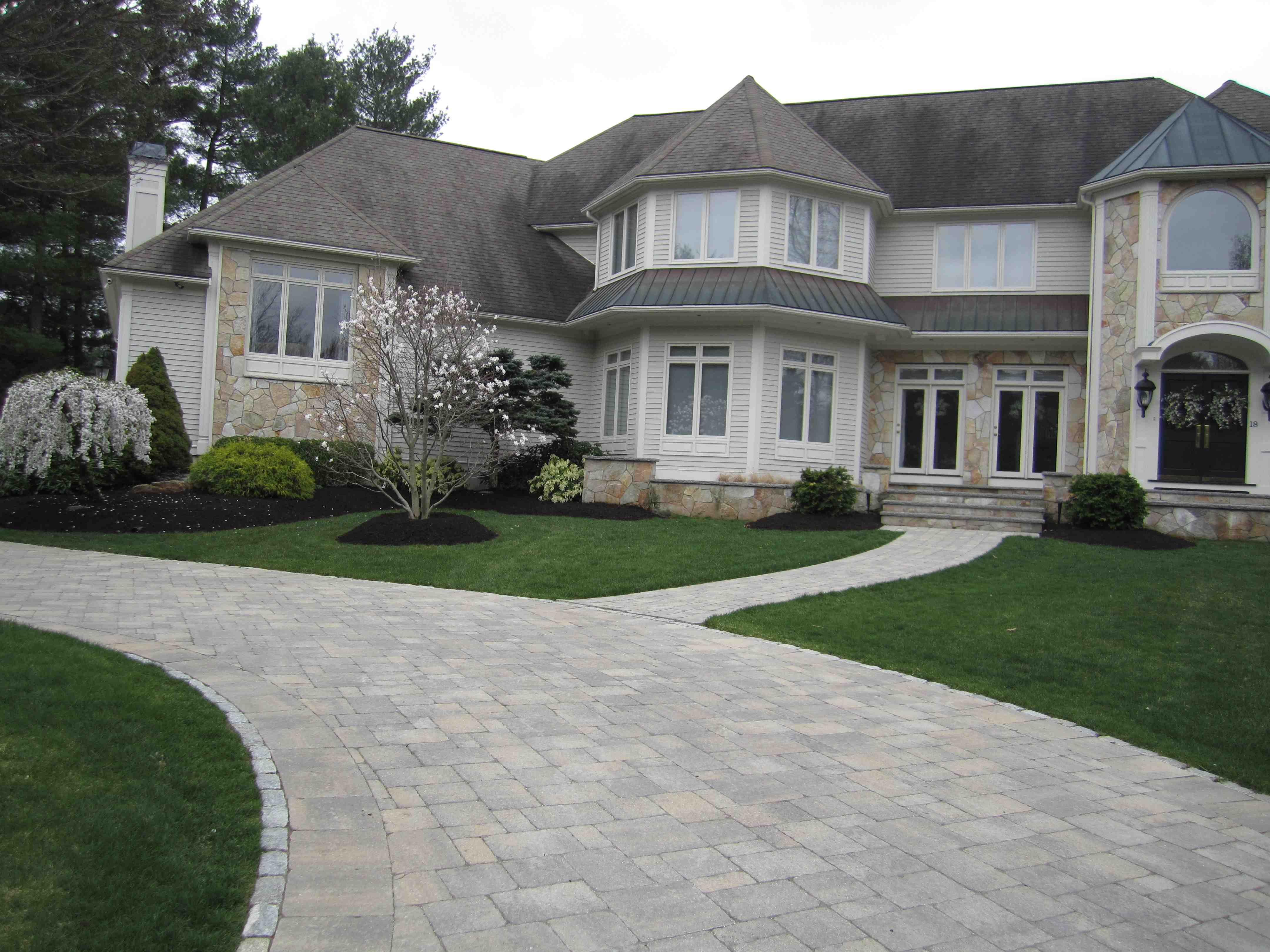 A beautiful, well-manicured lawn with vibrant green grass frames a picturesque residential home, enhancing its overall curb appeal and property value. - lawn layers near me